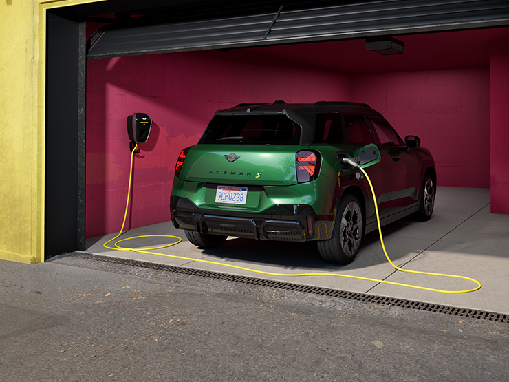 Vista posteriore della All-Electric MINI Aceman in British Racing Green in ricarica all’interno di un garage.  