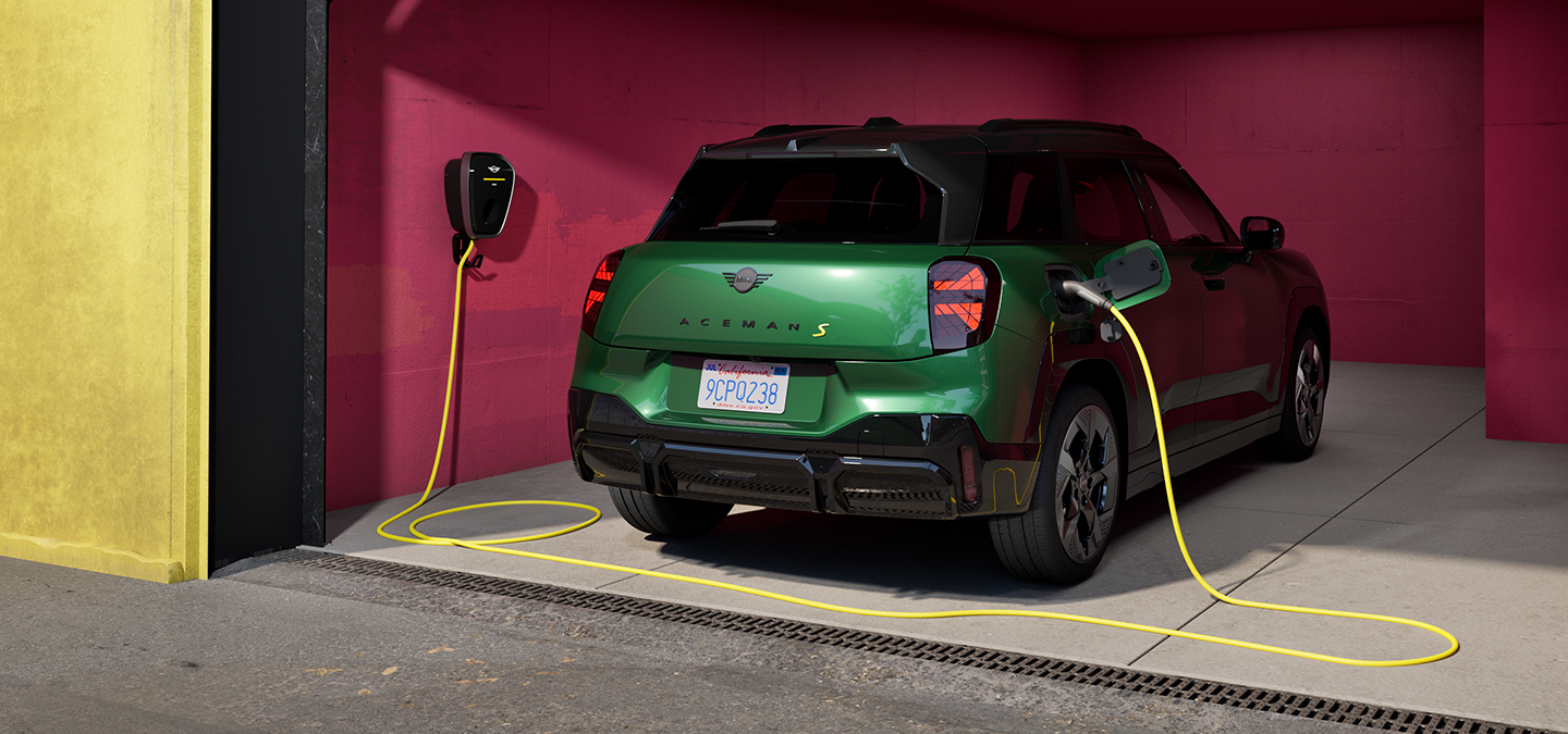 Vista posteriore della All-Electric MINI Aceman in British Racing Green in ricarica all’interno di un garage.  
