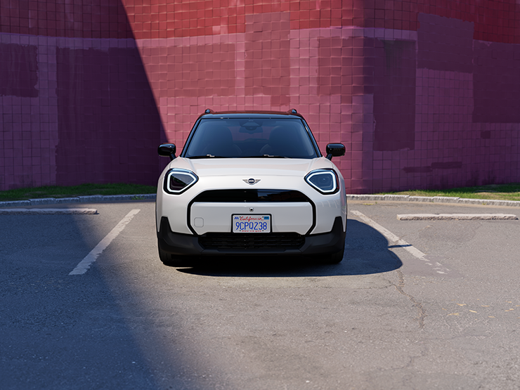 Vista frontale della All-Electric MINI Aceman in Nanuq White con tetto nero, parcheggiata.