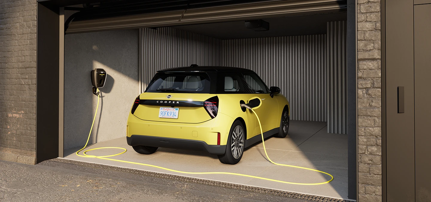 Vue arrière d’une MINI Cooper Electric Sunnyside Yellow en cours de recharge dans un garage. 
