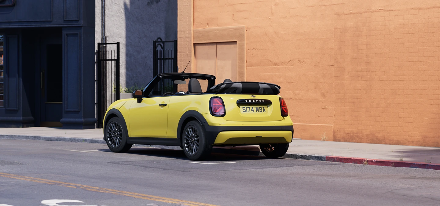 Ansicht von hinten links auf ein geparktes MINI Cooper Cabrio in Sunnyside Yellow.