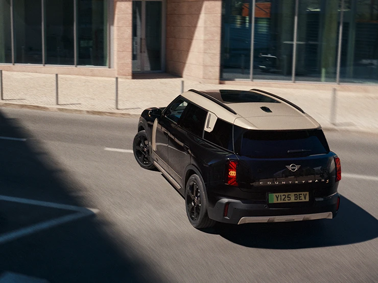 Ansicht von hinten oben eines vollelektrischen MINI Countryman in Midnight Black mit Dach in Vibrant Silver.