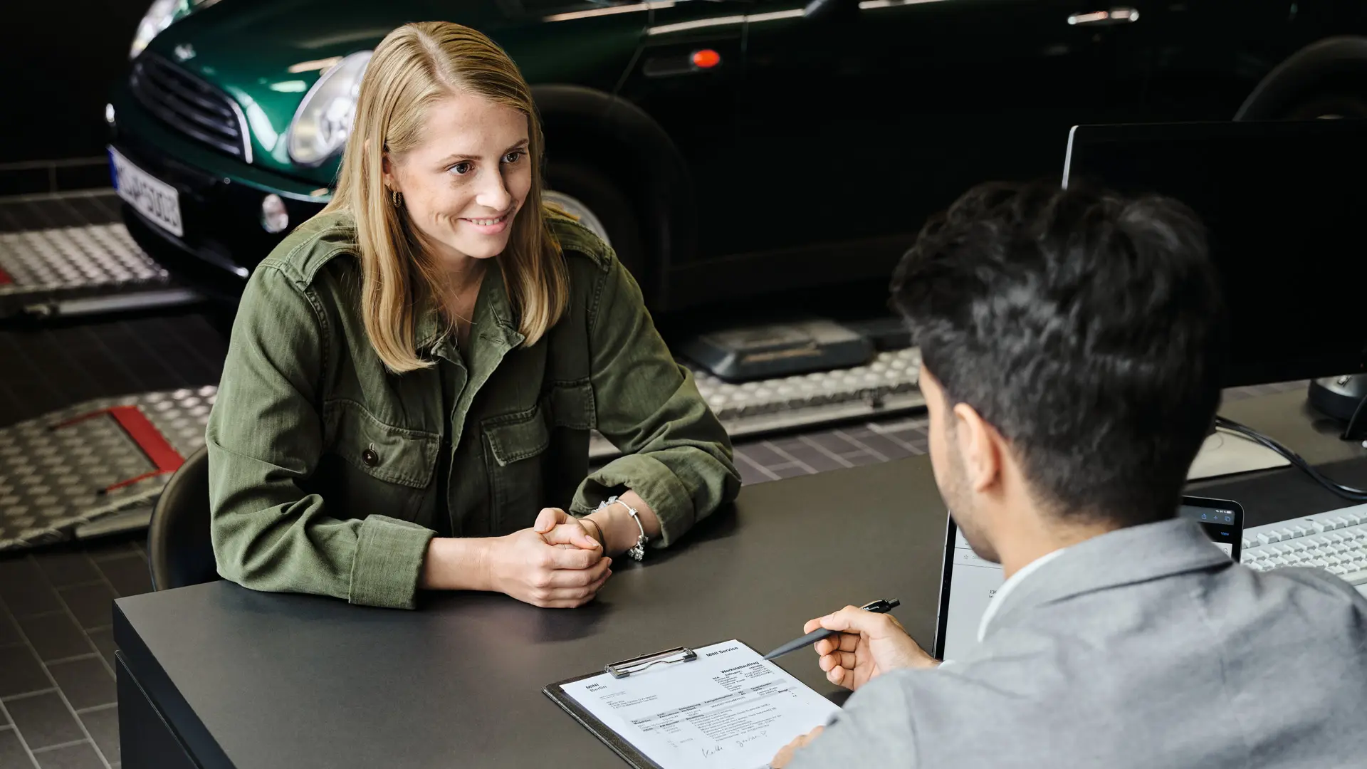 Centro MINI con consulente che consiglia al cliente le opzioni di assistenza; entrambi sono seduti a un tavolo.