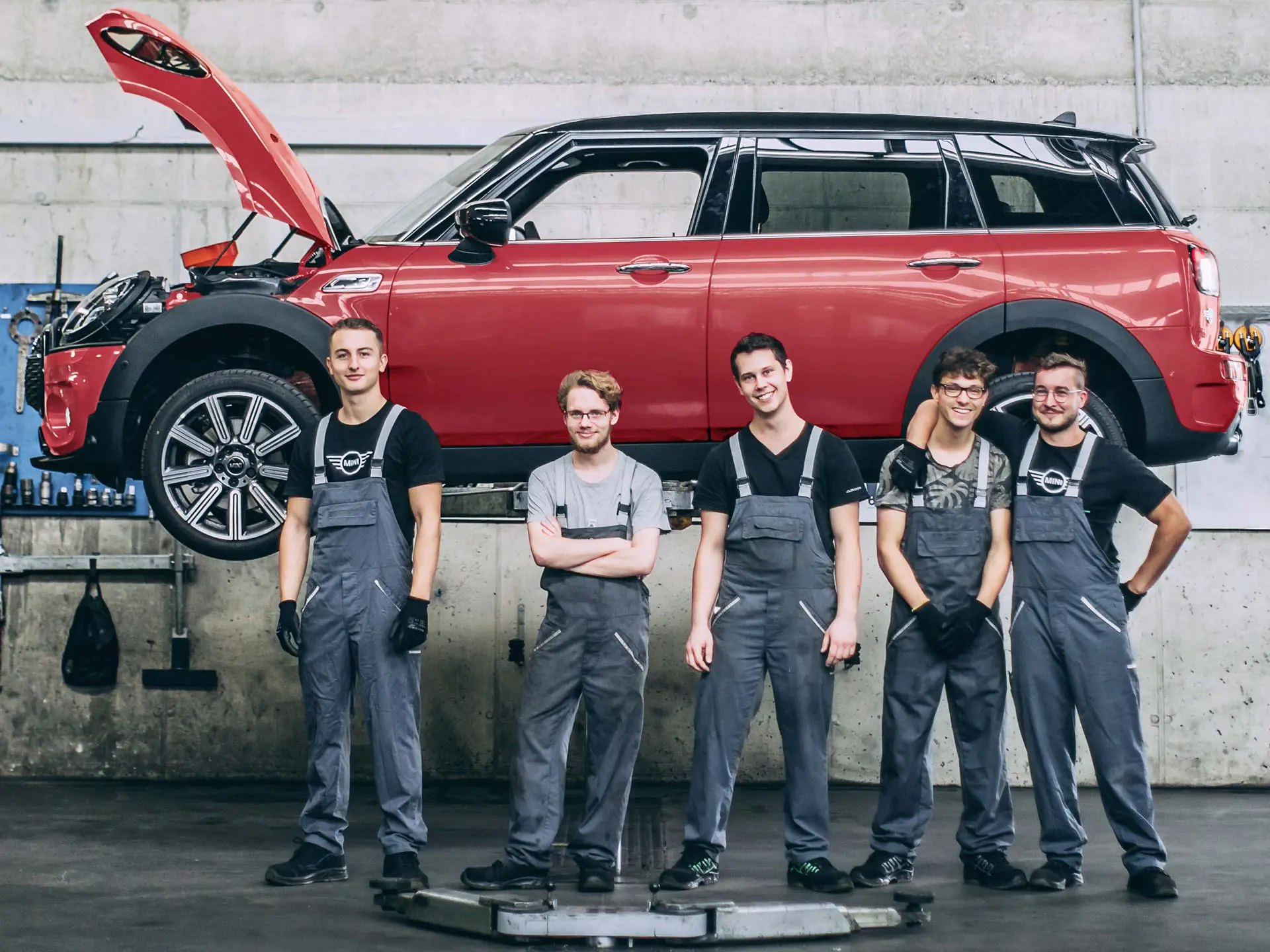 Addetti al servizio assistenza MINI davanti a una MINI Countryman su un ponte sollevatore.