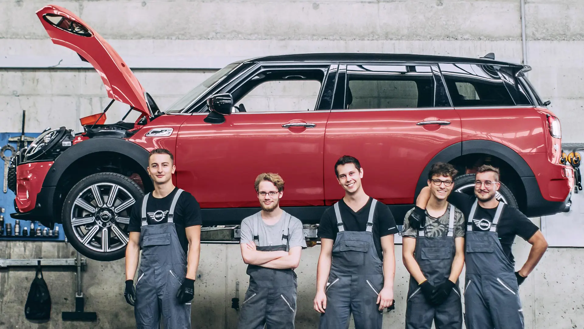 Addetti al servizio assistenza MINI davanti a una MINI Countryman su un ponte sollevatore.