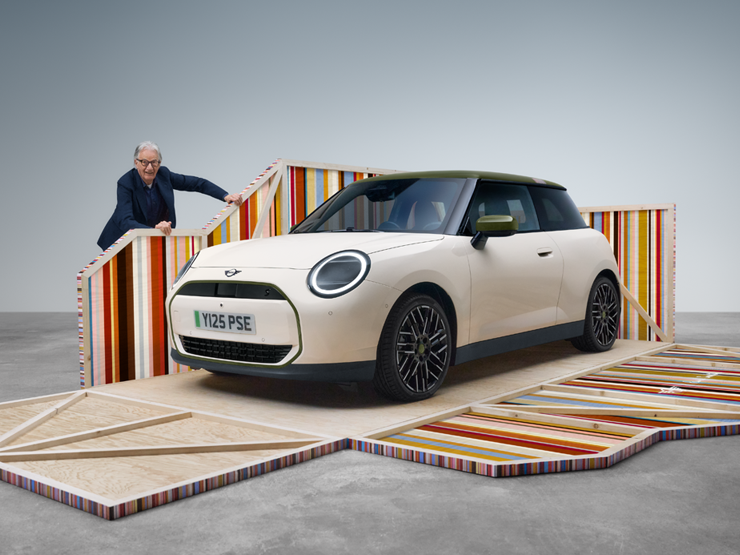 Vista laterale della parte anteriore della MINI Cooper Paul Smith Edition 100% elettrica in Inspired White con il designer Paul Smith