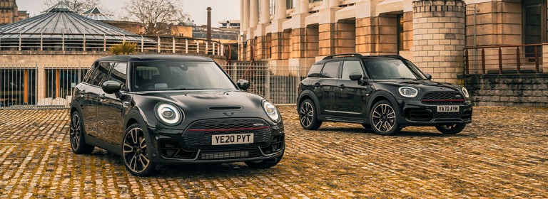 MINI Clubman und MINI Countryman in Dreiviertel-Seitenansicht vor Gebäude.