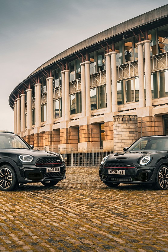 MINI Clubman und MINI Countryman in Dreiviertel-Seitenansicht vor Gebäude.