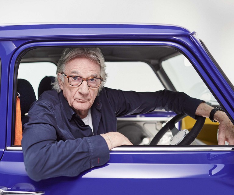 Paul Smith in his MINI Recharged, looking out of the window into the camera. An elbow hangs loosely over the lowered window. 