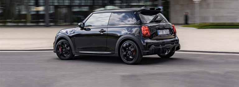 MINI JCW vue de côté roulant devant un bâtiment