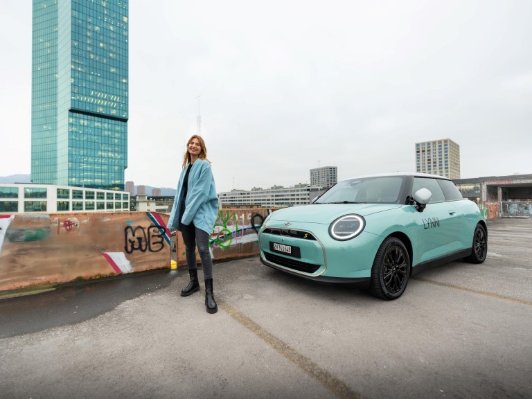 Vue d’en haut d’une MINI avec branding hôtel 25hours sur le toit garée sur une place pluvieuse