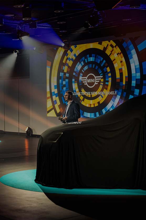 Due MINI sul palco coperte da un telo e illuminate da riflettori Due MINI sul palco coperte da un telo nero e illuminate da riflettori